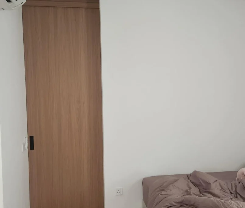 Minimalist bedroom with wood sliding door and partially visible bed —Project by Ray & Mist Renovation Sdn. Bhd.