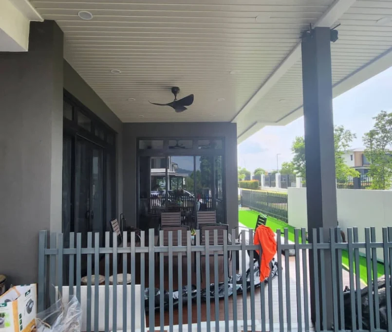 Covered outdoor patio with ceiling fan, dining table, and grey picket fence —Project by Ray & Mist Renovation Sdn. Bhd.