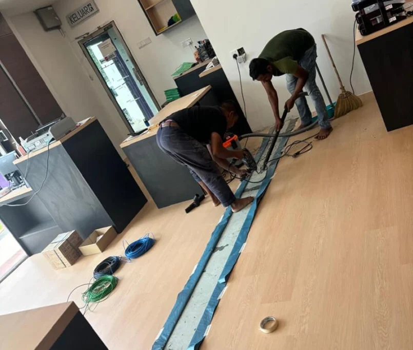 Two workers doing floor wiring installation in a renovated office space —Project by Ray & Mist Renovation Sdn. Bhd.