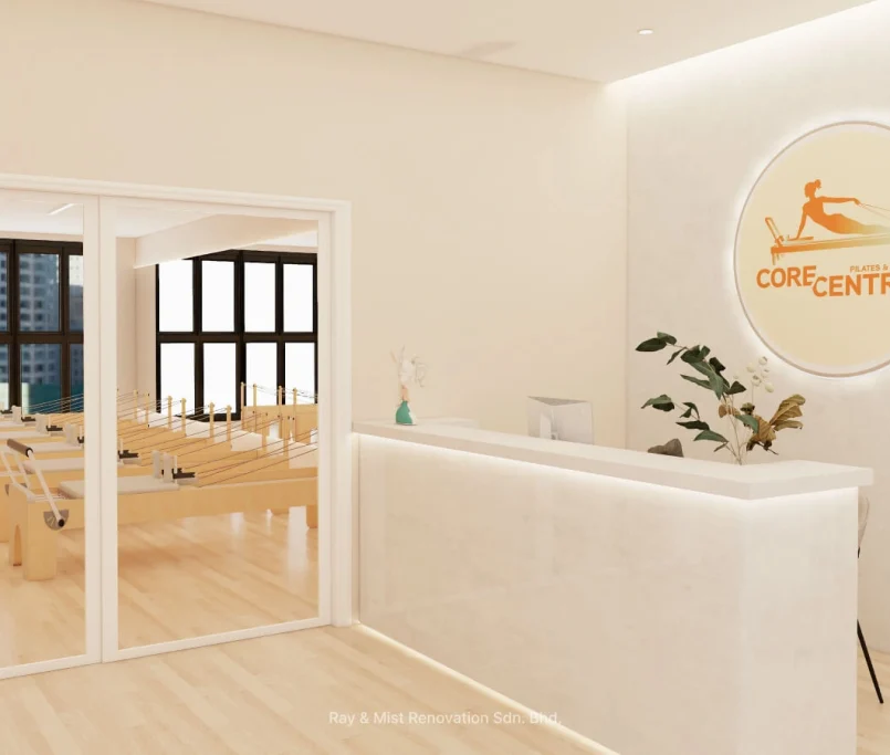 Reception area of Corecentric Pilates & Fitness studio with illuminated logo, minimalist counter, and reformer machines visible through glass — — Project by Ray & Mist Renovation Sdn. Bhd.