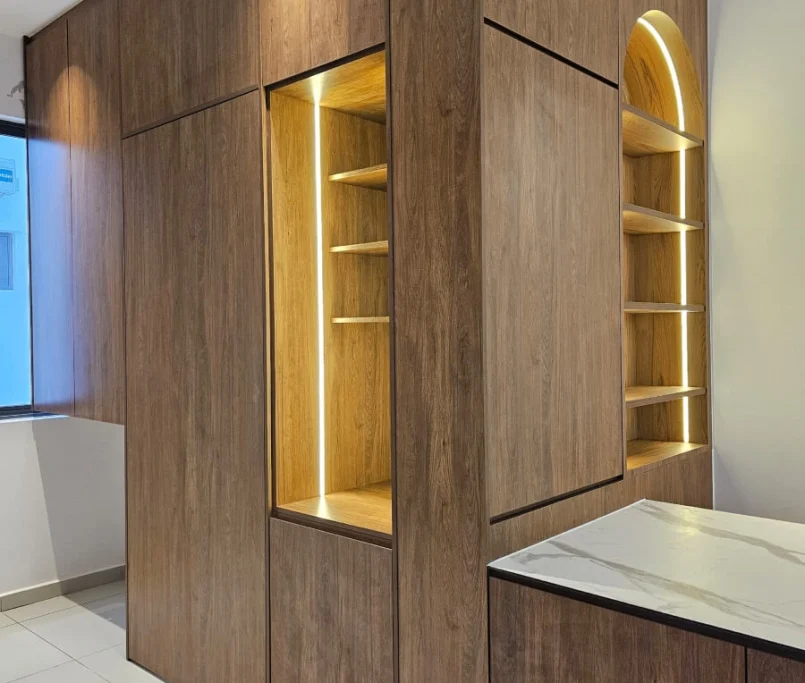 Built-in wooden cabinets with illuminated vertical and arched open shelving next to a marble-top counter —Project by Ray & Mist Renovation Sdn. Bhd.