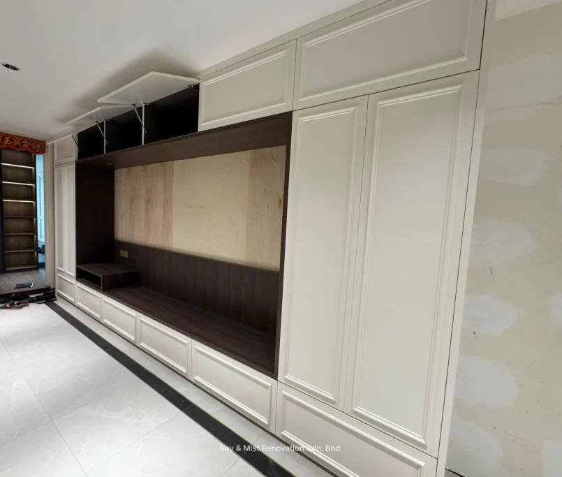 Built-in wall cabinet with cream doors and walnut interior finish, featuring open compartments and overhead storage — Project by Ray & Mist Renovation Sdn. Bhd.