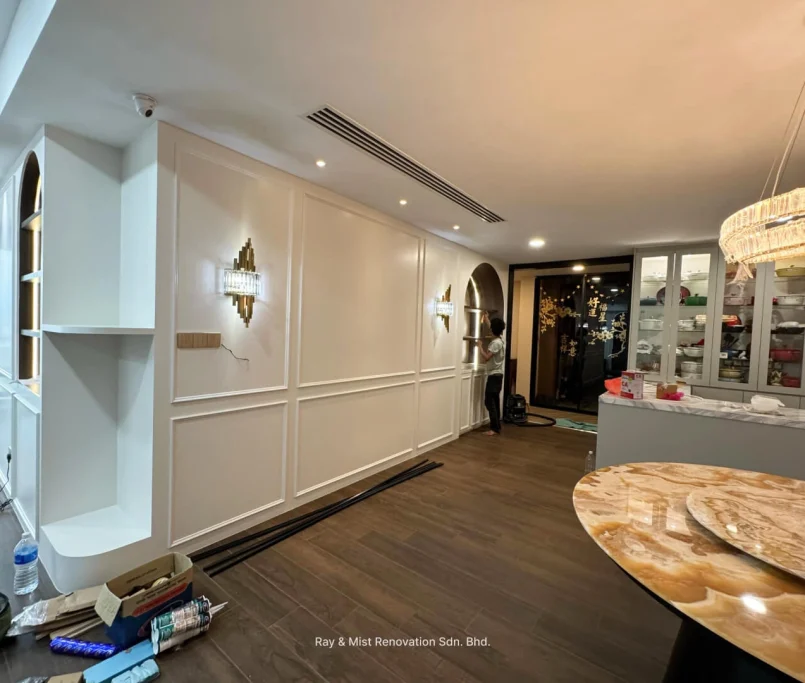 Elegant dining area with white panelled feature wall, glass display cabinet, and chandelier — Project by Ray & Mist Renovation Sdn. Bhd.