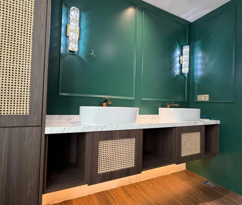 Double vanity unit with marble countertop, vessel sinks, and cane-front drawers set against an emerald green panel wall — Project by Ray & Mist Renovation Sdn. Bhd.