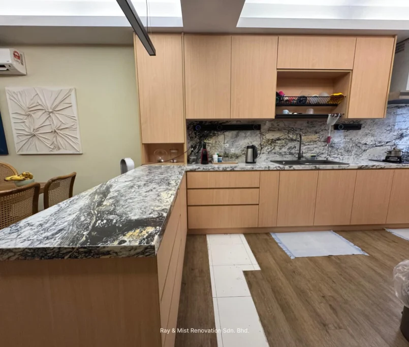 Open-concept kitchen with light wood cabinetry and dramatic marble surfaces — Project by Ray & Mist Design Sdn. Bhd.